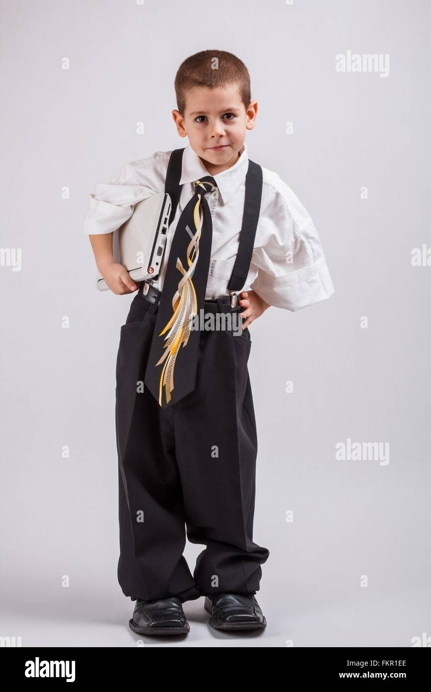 Ritratto di un ragazzo che indossa abiti di grandi dimensioni con il computer portatile Foto Stock