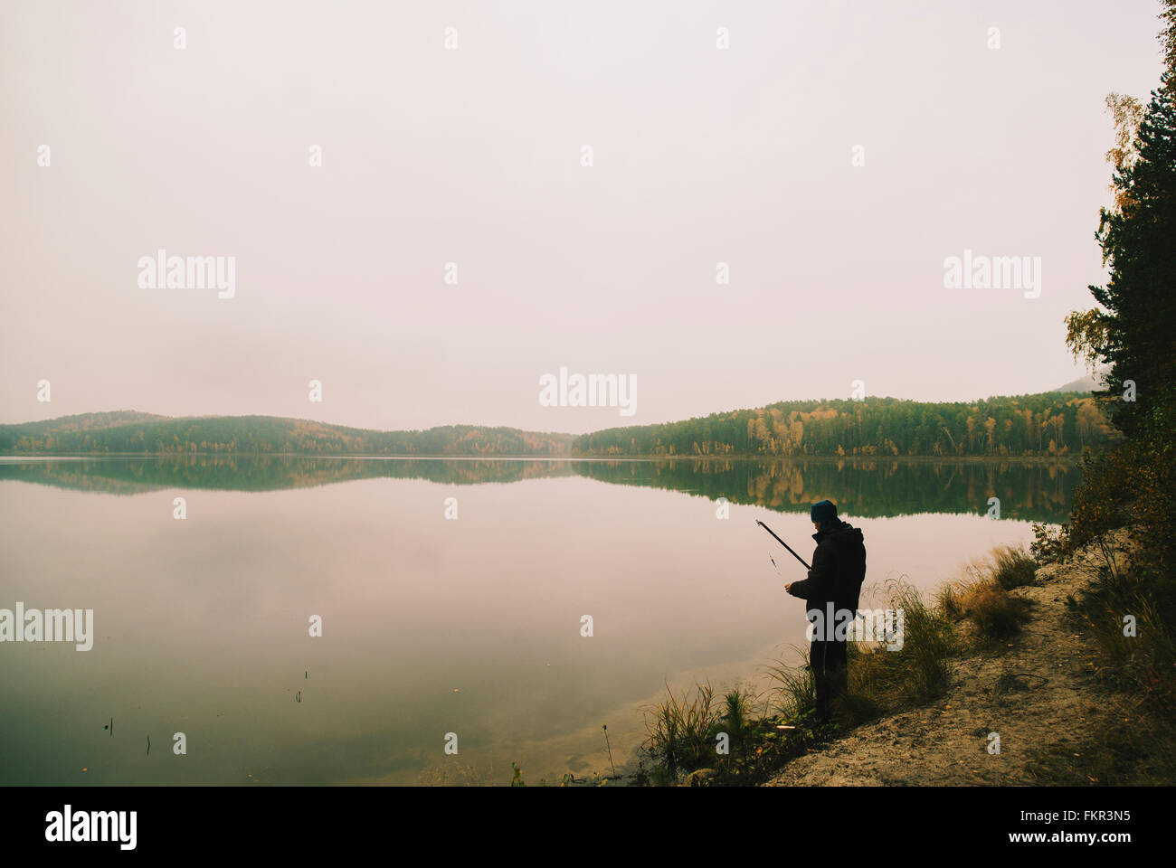 L'uomo la pesca in lago remoto Foto Stock