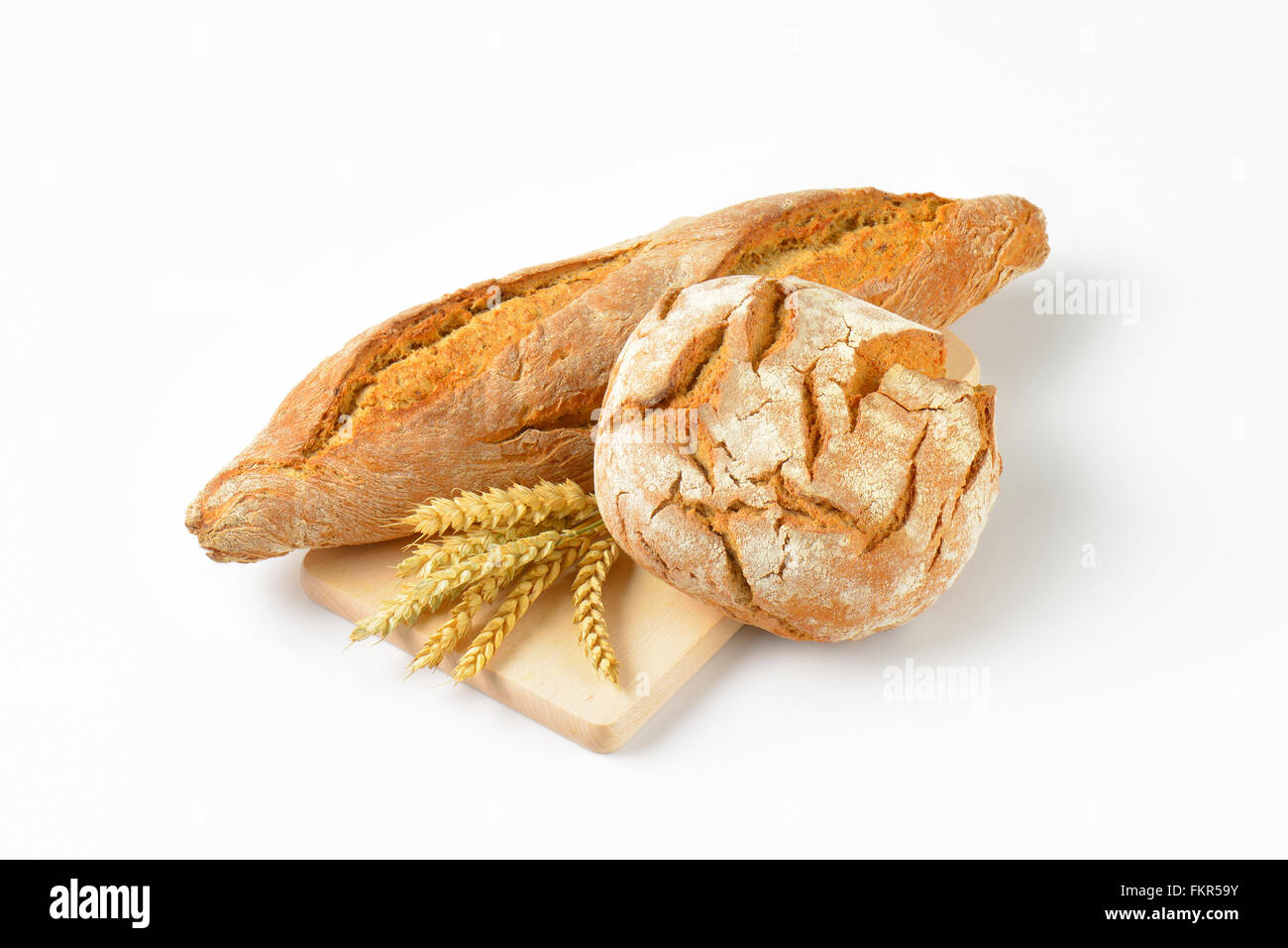 Il pane appena sfornato e baguette sul tagliere di legno Foto Stock