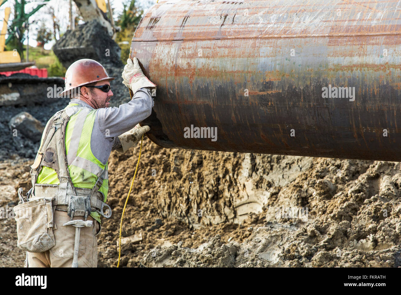 Lavoratore caucasica tubazione di trasporto al sito in costruzione Foto Stock