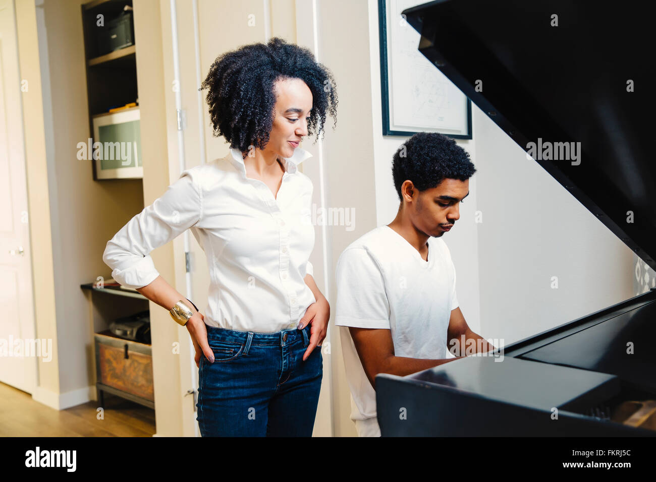 Guardare la madre figlio suonare il pianoforte Foto Stock