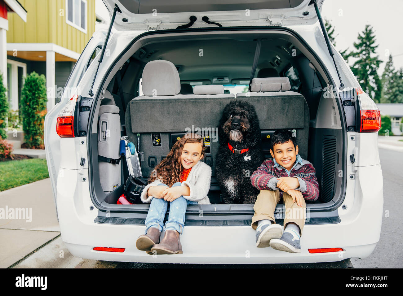 Razza mista bambini seduti con il cane in auto berlina Foto Stock