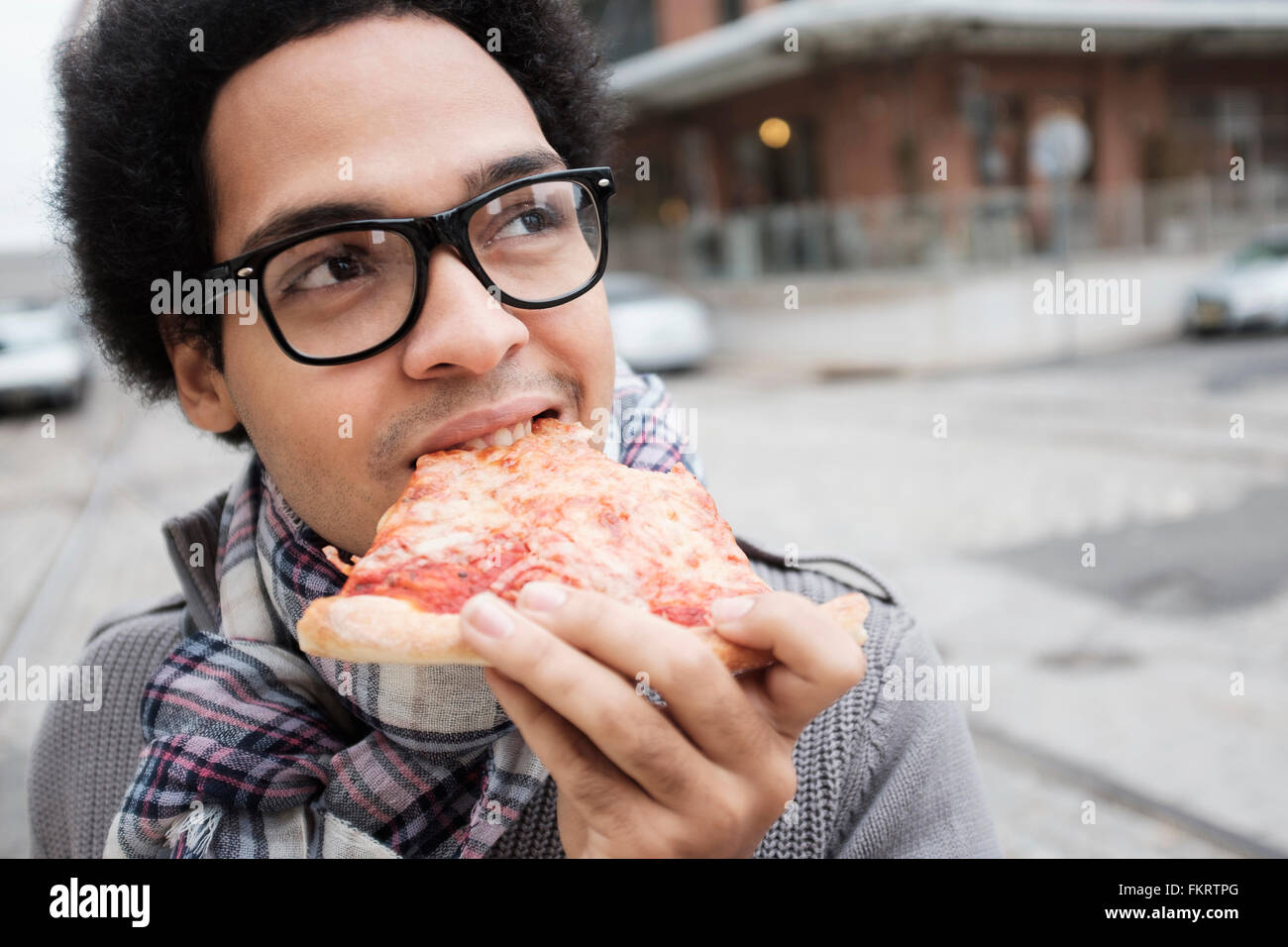 Razza mista uomo mangiare la pizza all'aperto Foto Stock