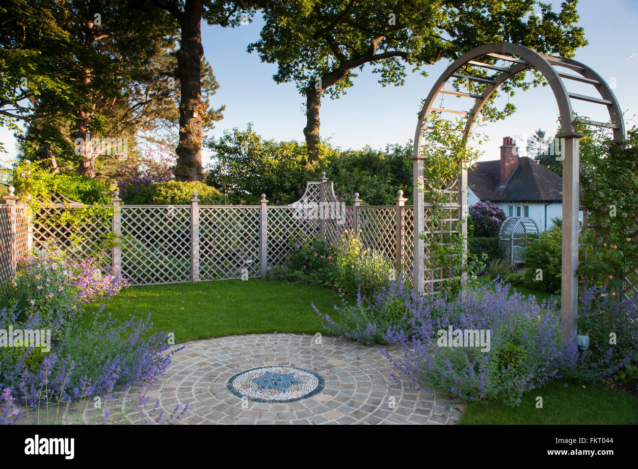 Piante, opere d'arte del mosaico, schermata trellis & arbour archway in estate - bella e tradizionale e paesaggistici, progettato giardino - West Yorkshire, Inghilterra, Regno Unito. Foto Stock