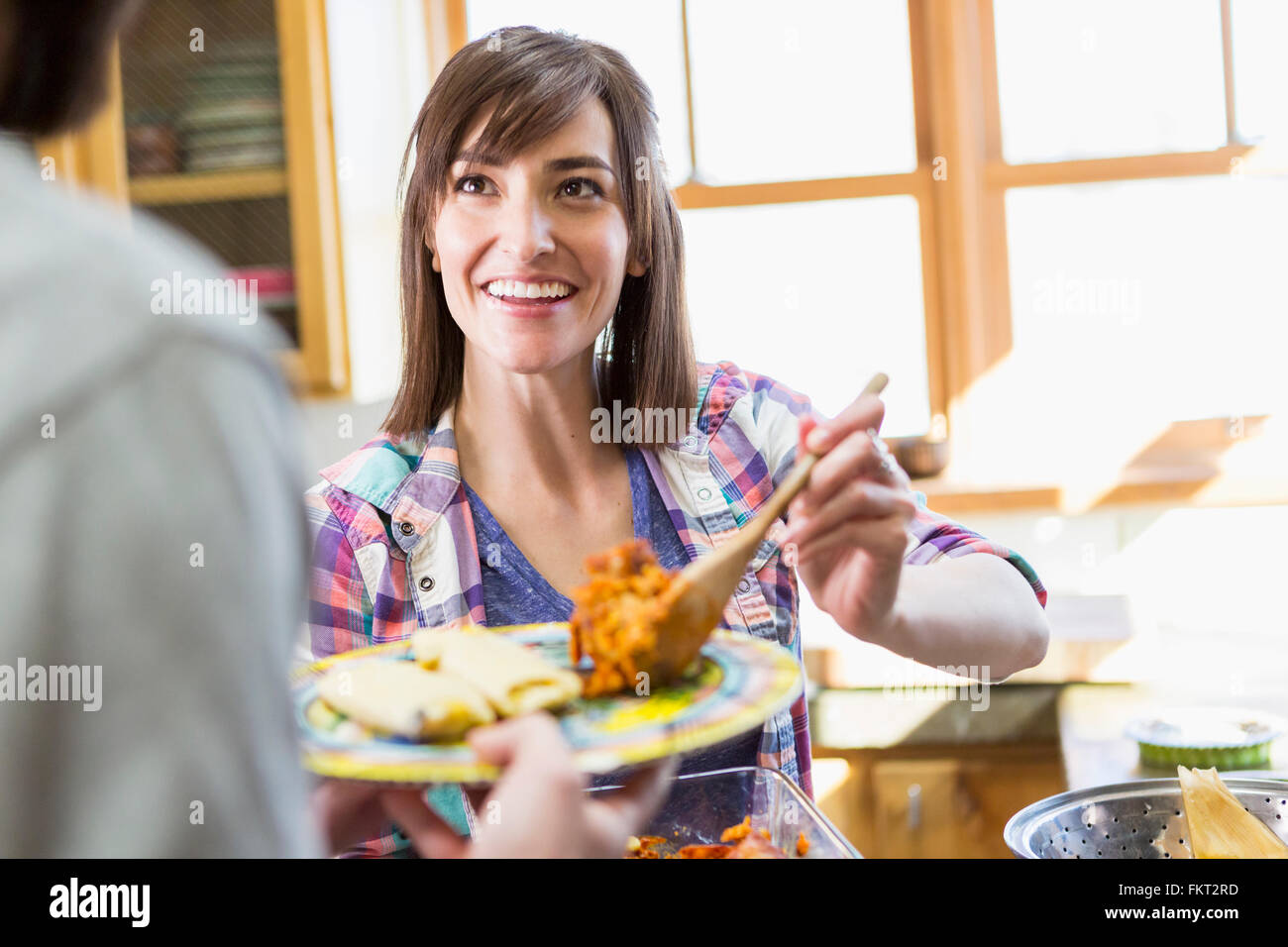 Donna ispanica che serve il ragazzo in cucina Foto Stock