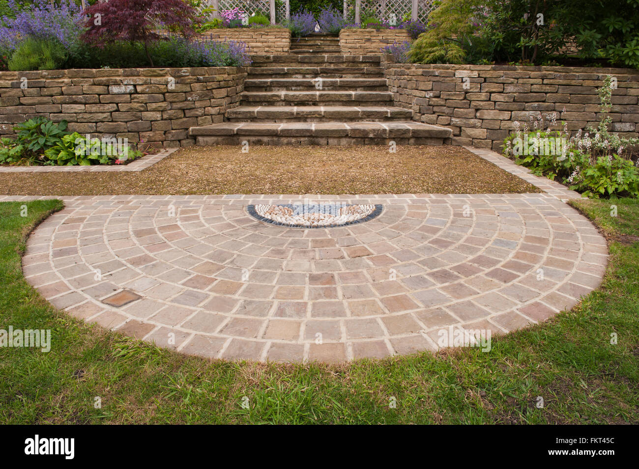 Mosaico di ciottoli, pavimentazione, piante, passaggi, muro di pietra e terrazzamenti - tradizionale, progettato e paesaggistici, giardino, Burley in Wharfedale, nello Yorkshire, Inghilterra. Foto Stock
