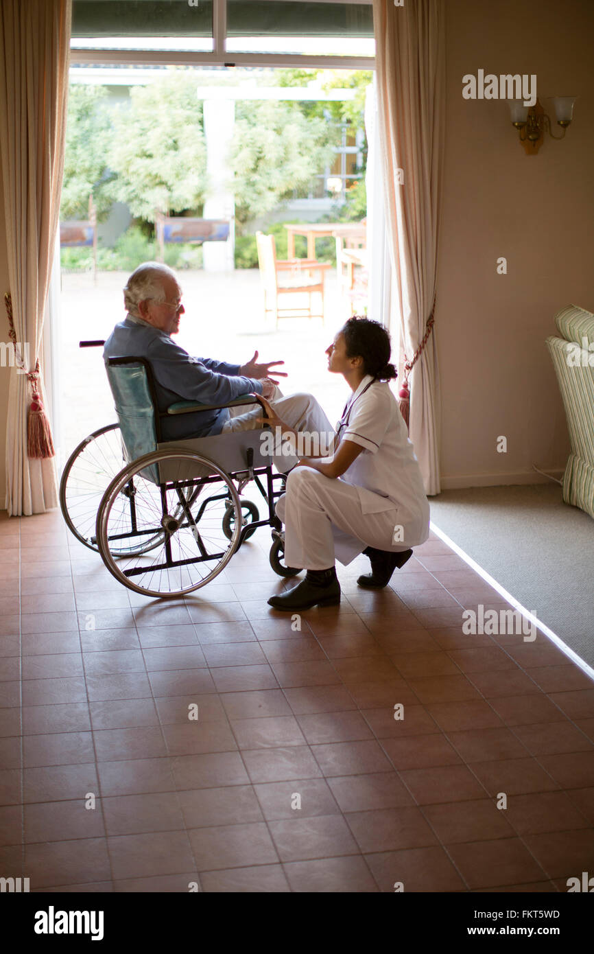 L'infermiera di parlare al paziente in sedia a rotelle Foto Stock