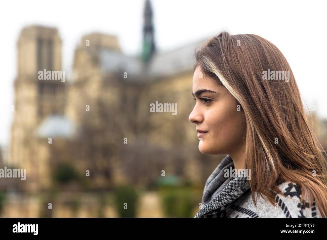 Vista laterale della giovane donna, la cattedrale di Notre Dame in background, Parigi, Francia Foto Stock