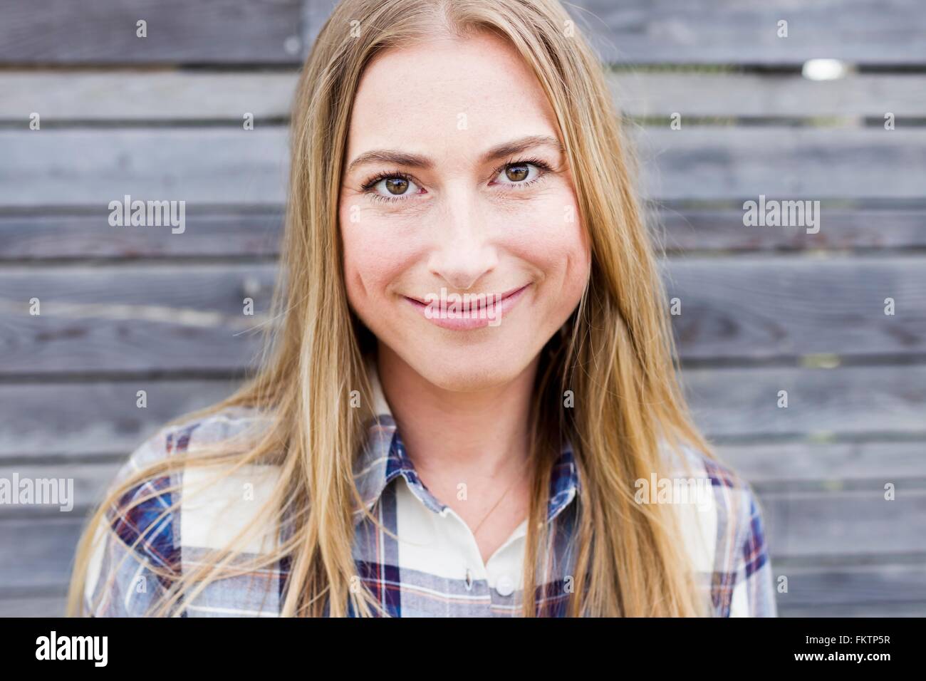 Metà donna adulta con capelli biondi sorridendo, ritratto Foto Stock