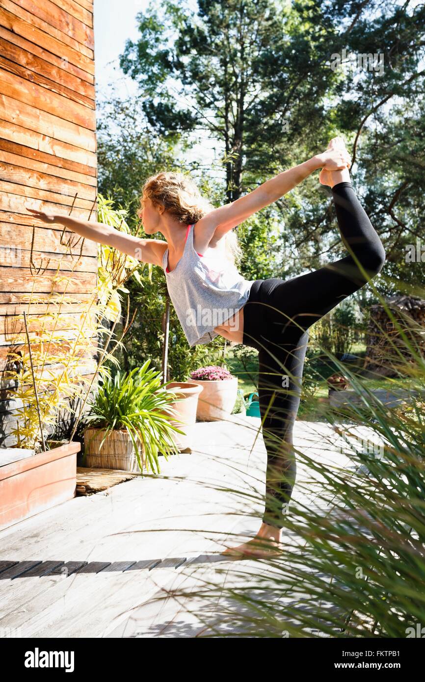 Giovane donna su una gamba sola con braccio fuori in posa di yoga Foto Stock