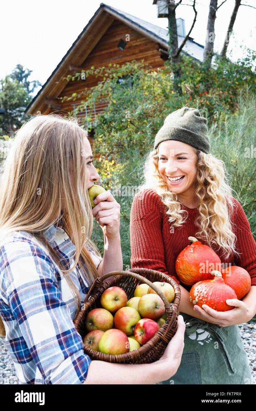 Due amici che trasportano homegrown produrre, una donna mangiare apple Foto Stock