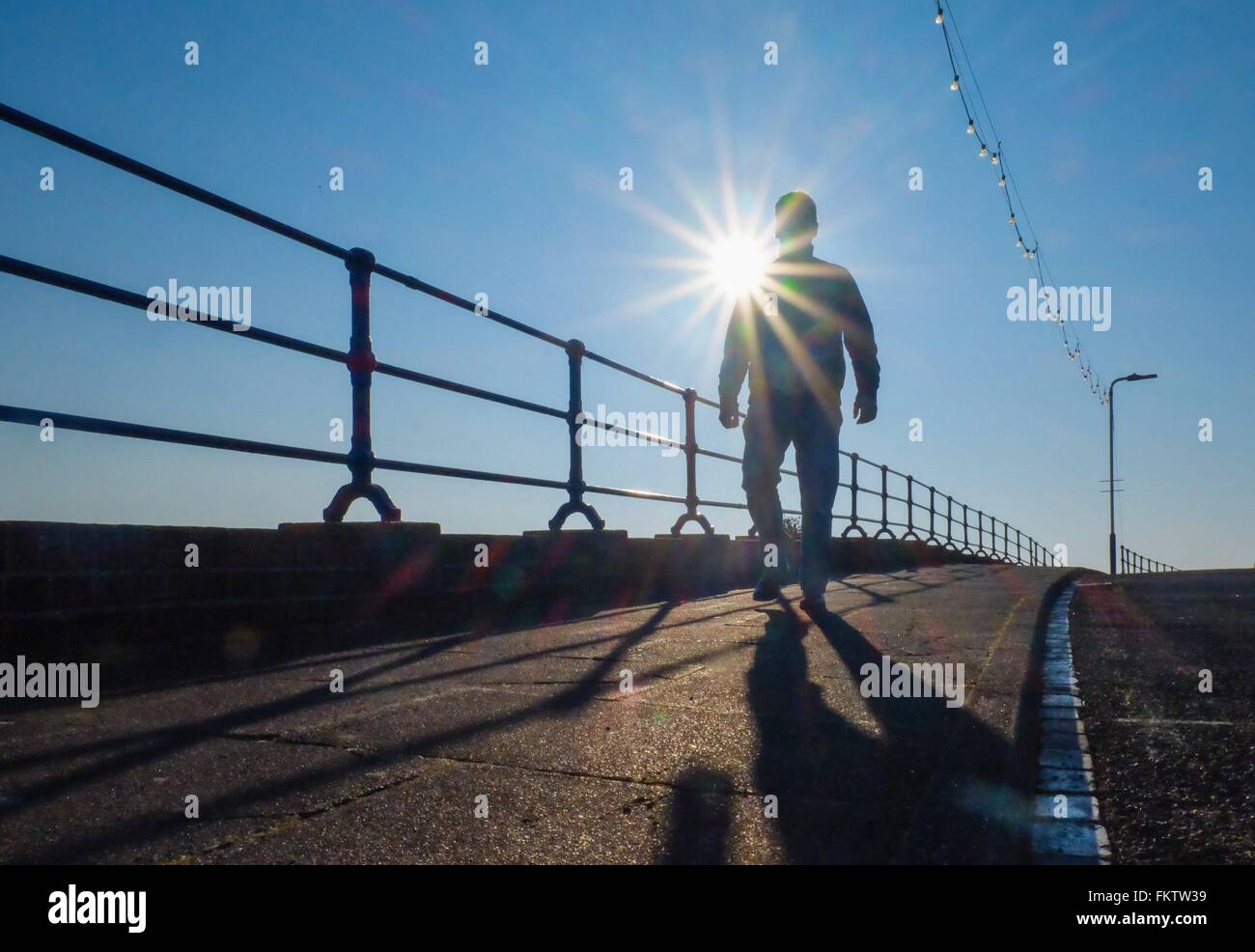 Basso angolo di vista stagliano uomo passeggiando sul lungomare Foto Stock