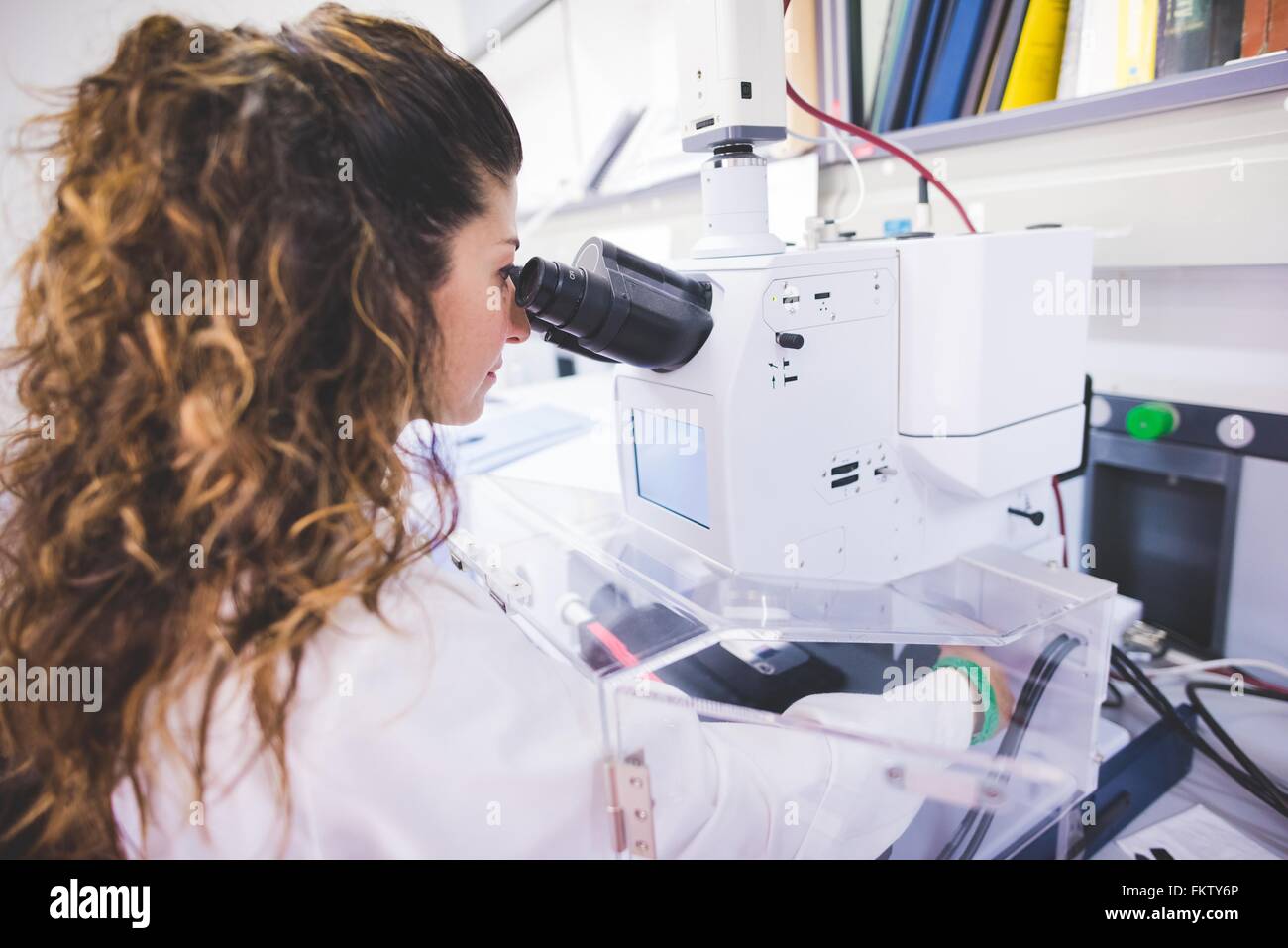 Donna scienziato utilizzando uno spettrofotometro FTIR, guardando a pellicola sottile di campione attraverso il microscopio FTIR Foto Stock