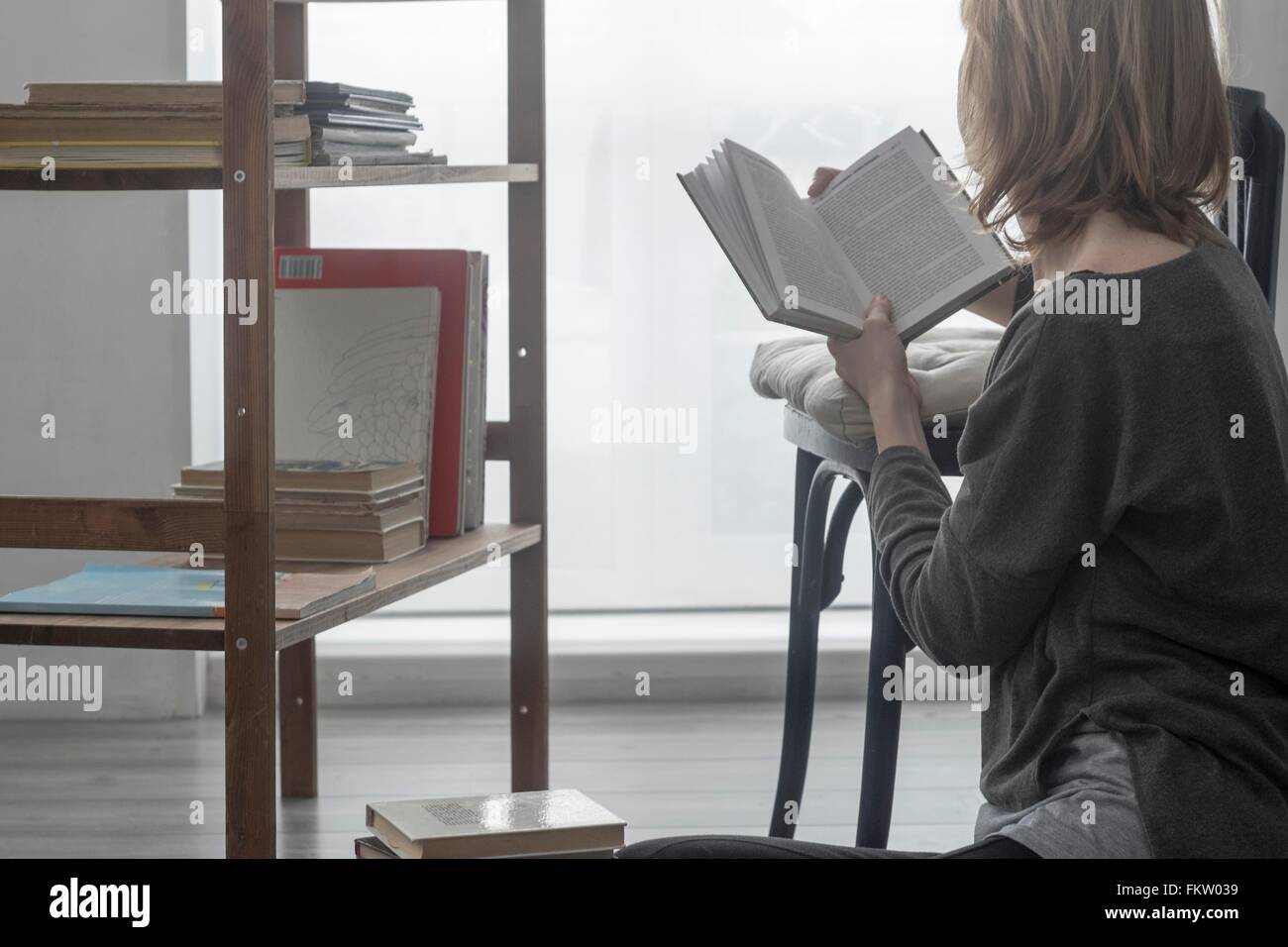 Donna seduta sul soggiorno piano la lettura di un libro Foto Stock