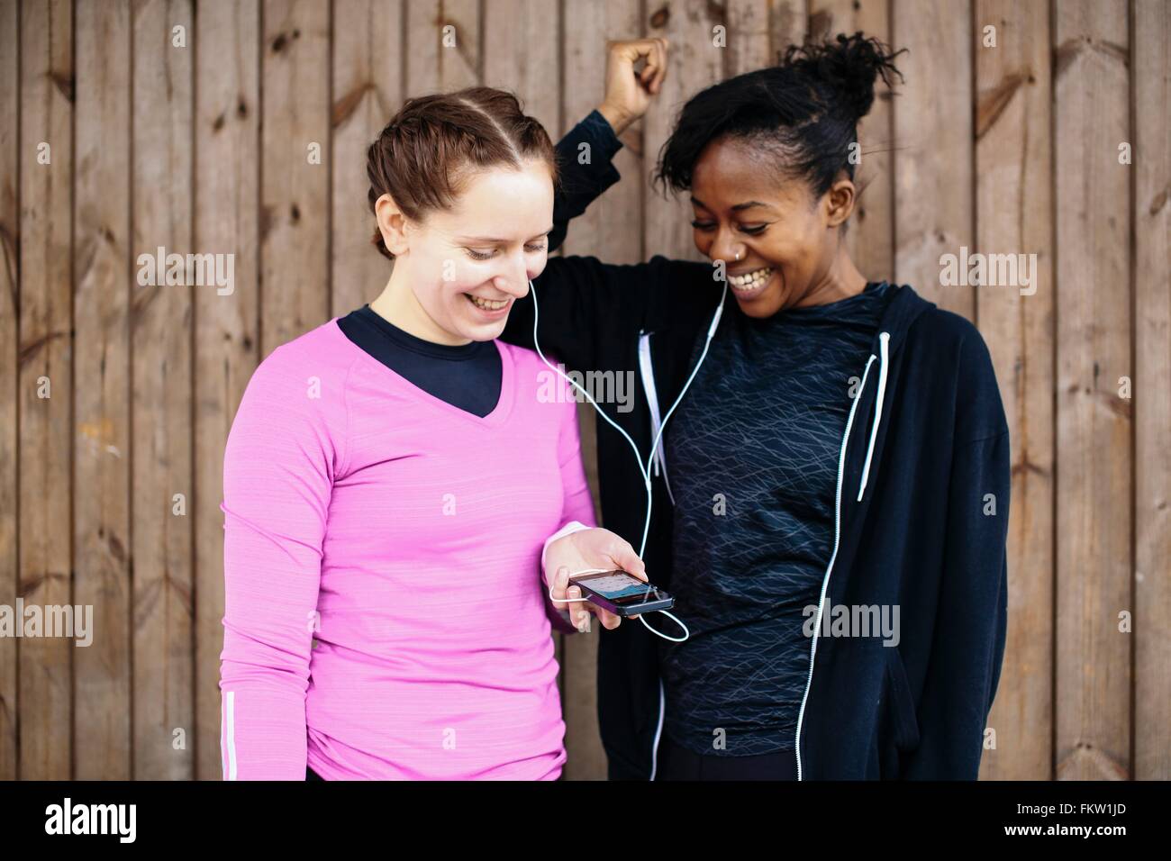 Due giovani donne capanna esterna di condivisione musica dello smartphone Foto Stock