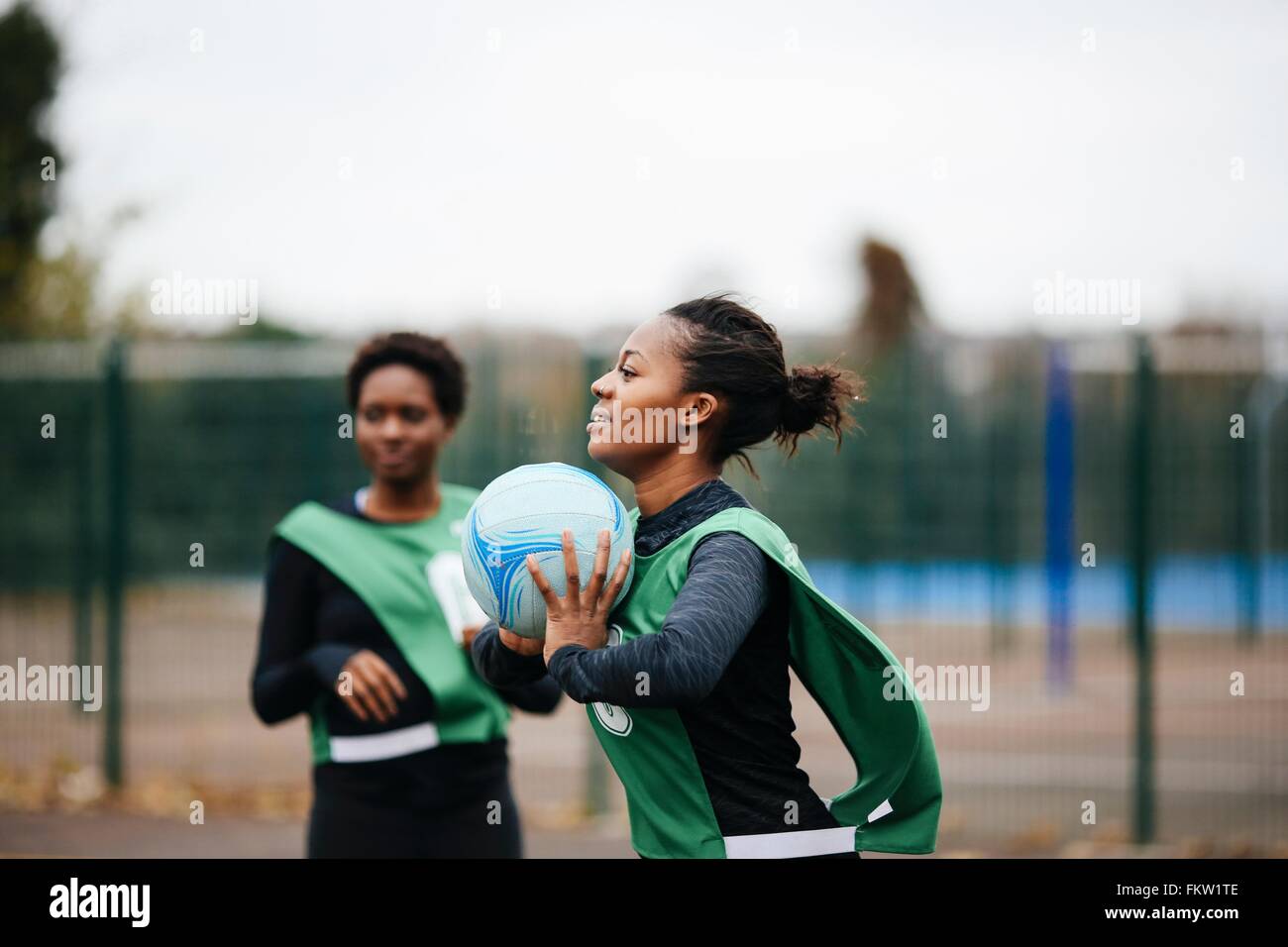 Giovane femmina adulta netball player a giocare su netball corte Foto Stock