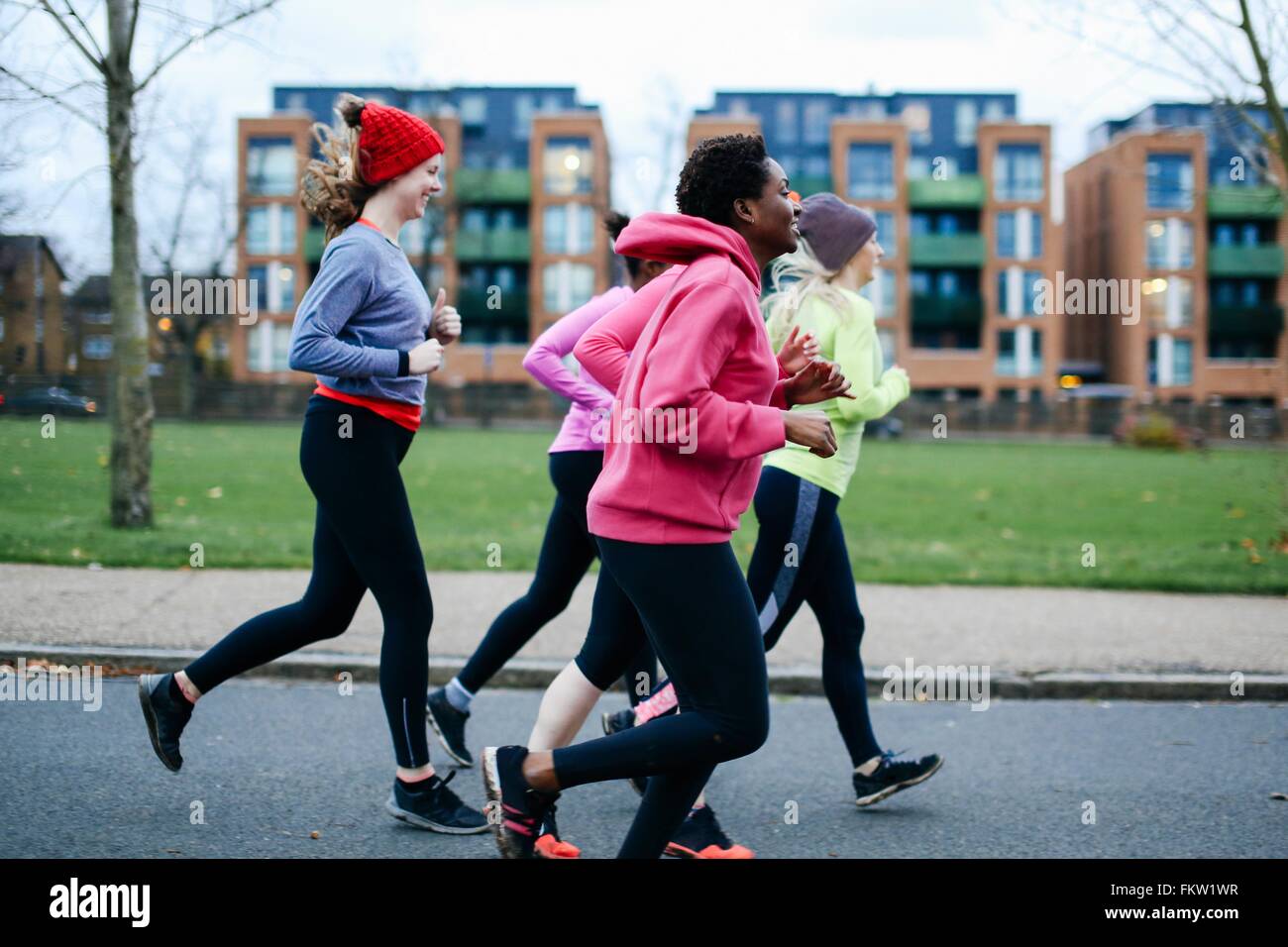 Cinque donne che corre lungo il marciapiede della città Foto Stock