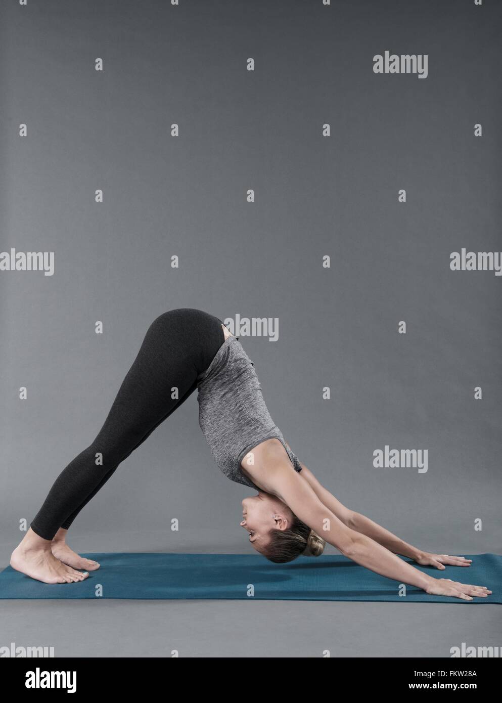 Giovane donna a praticare yoga e sfondo grigio Foto Stock