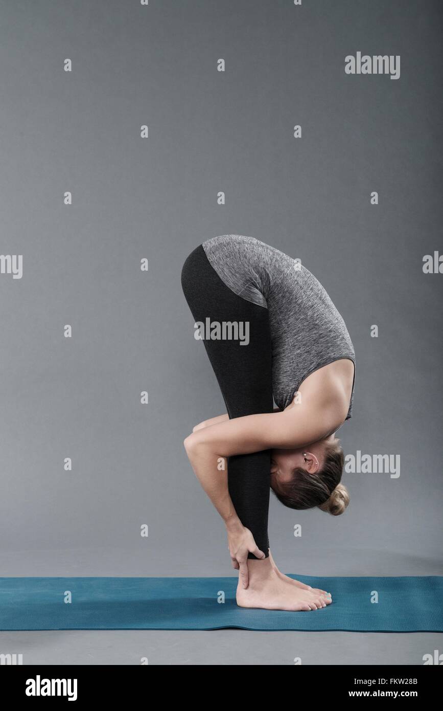 Giovane donna a praticare yoga e sfondo grigio Foto Stock