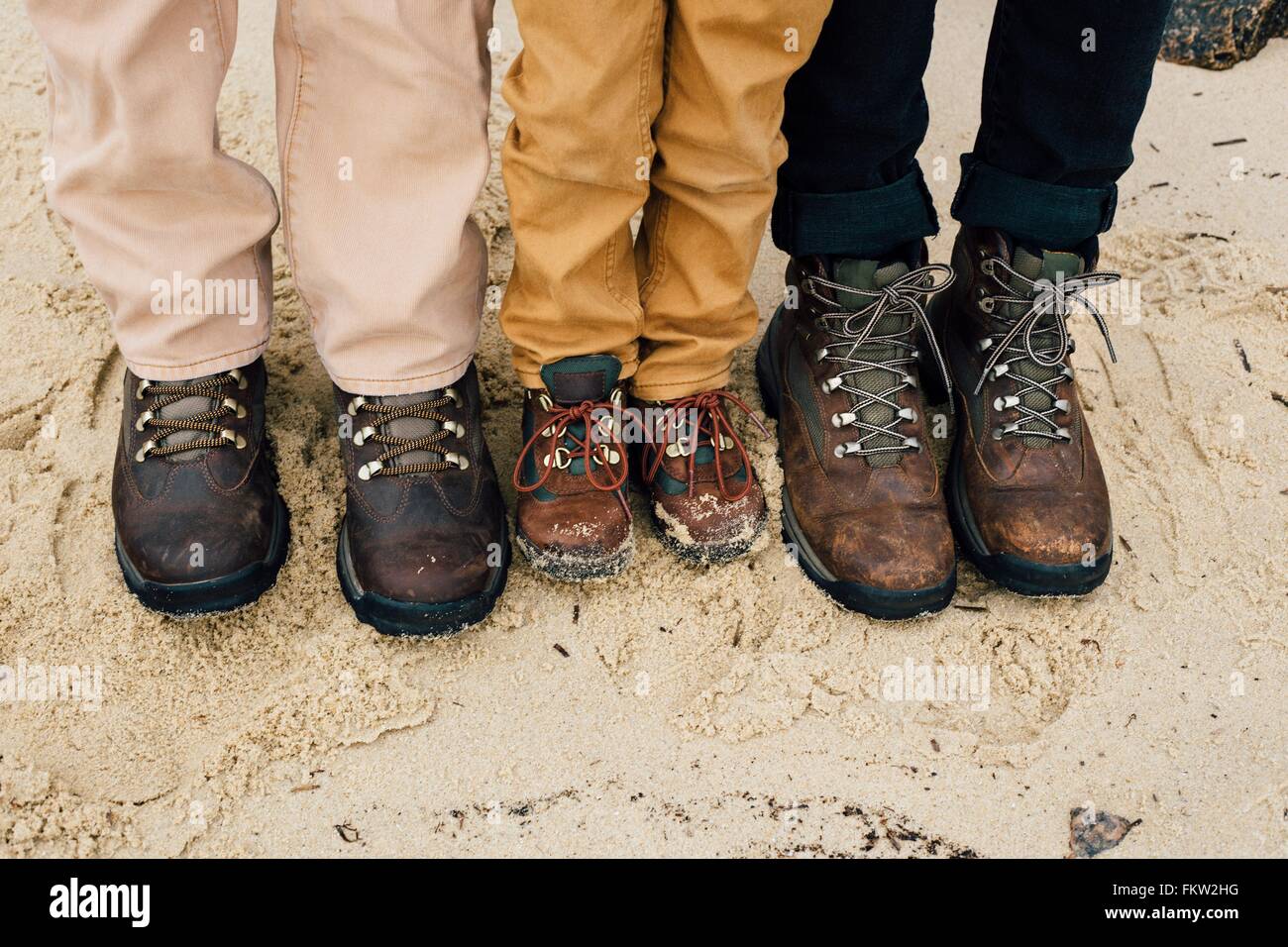 Padre in piedi con due bambini, focus su piedi Foto Stock