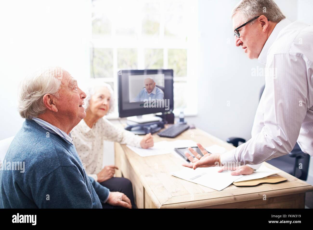 Business man in ufficio avente la discussione con coppia senior Foto Stock