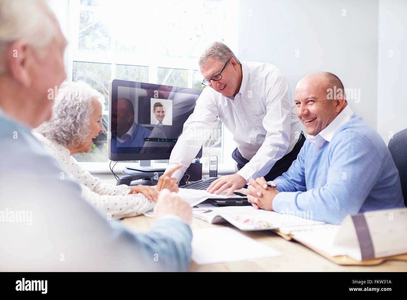 Gli uomini d'affari in fice avente la discussione con coppia senior Foto Stock