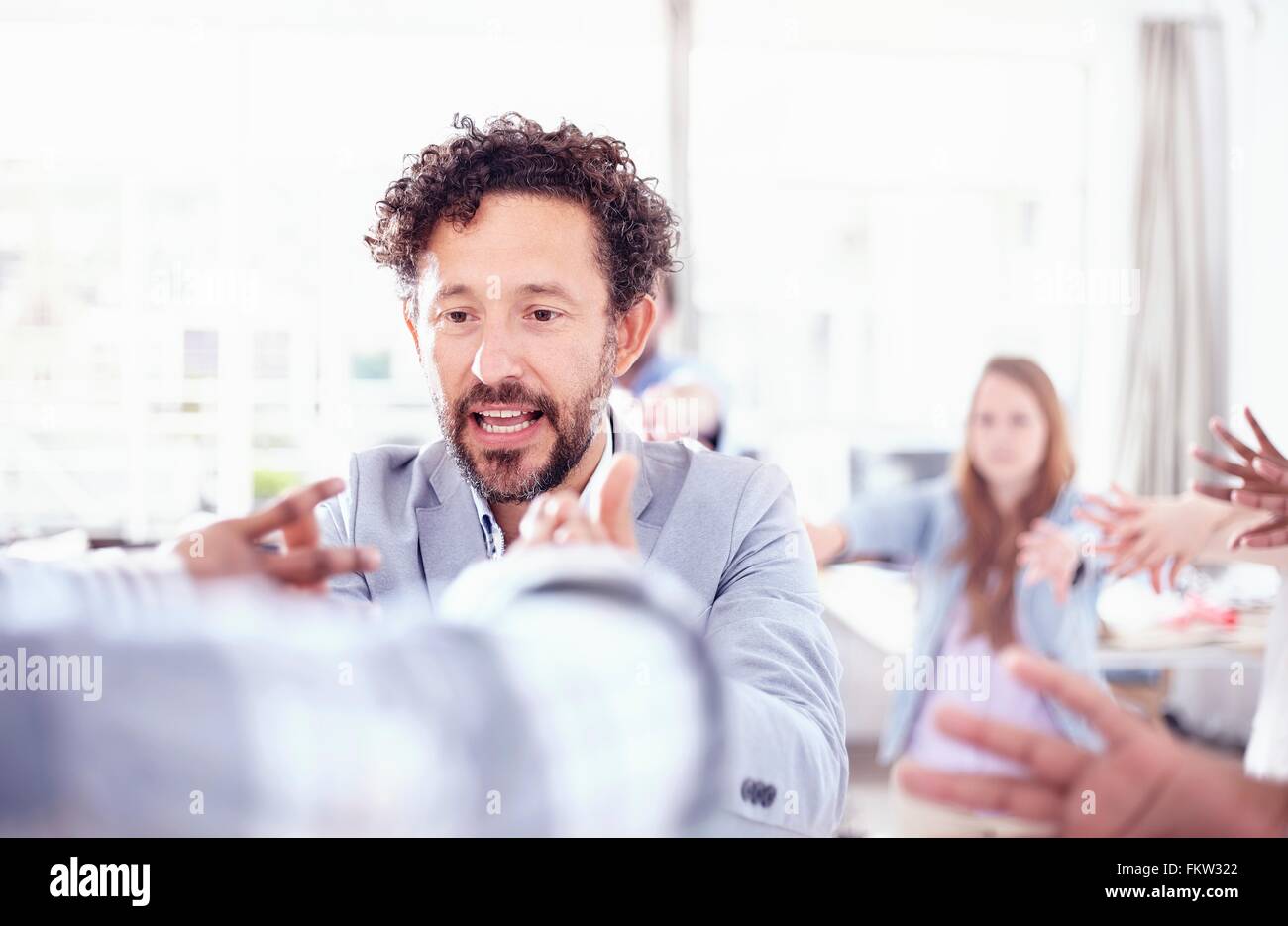 Barbuto uomo maturo in team building permette di parlare tenendo le mani sollevate sorridente Foto Stock