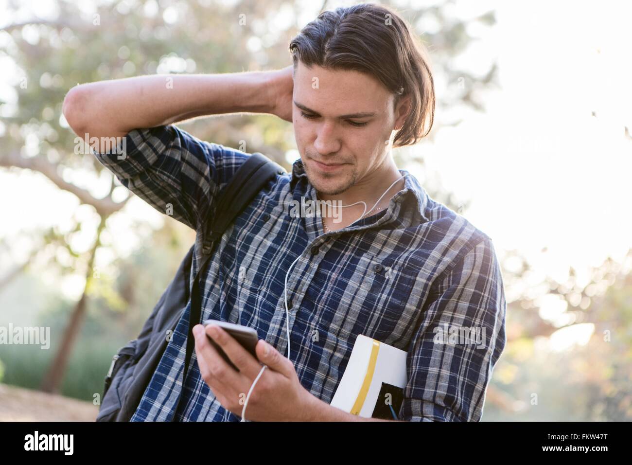 Angolo di visualizzazione del giovane, mano a testa, guardando verso il basso in corrispondenza di smartphone Foto Stock