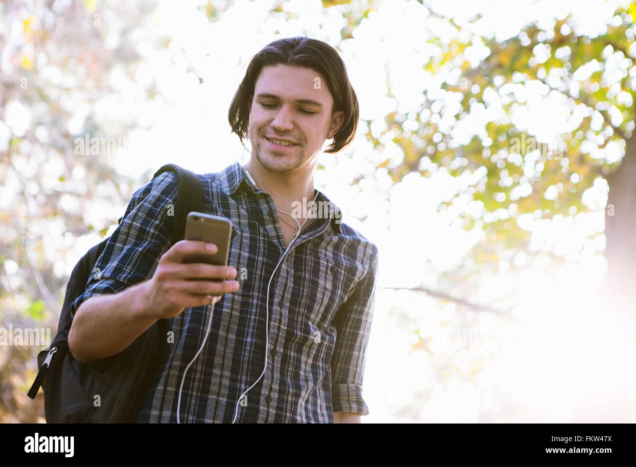 Basso angolo vista del giovane azienda smartphone guardando giù sorridente Foto Stock