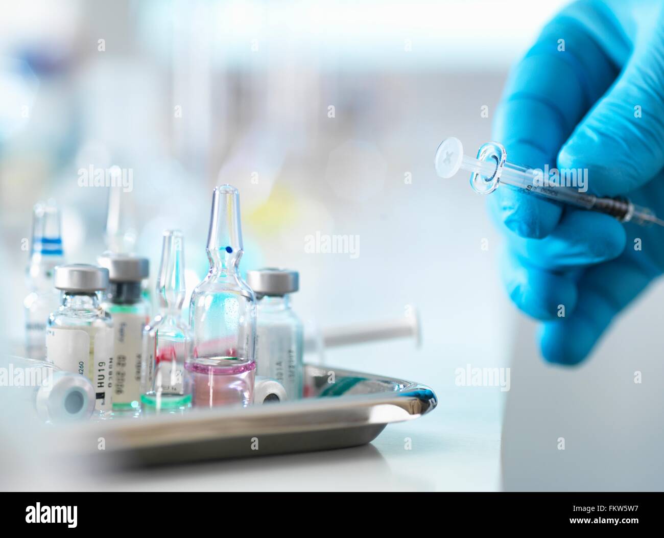 Medico posizionando la siringa torna sul vassoio con fiale di farmaci Foto Stock