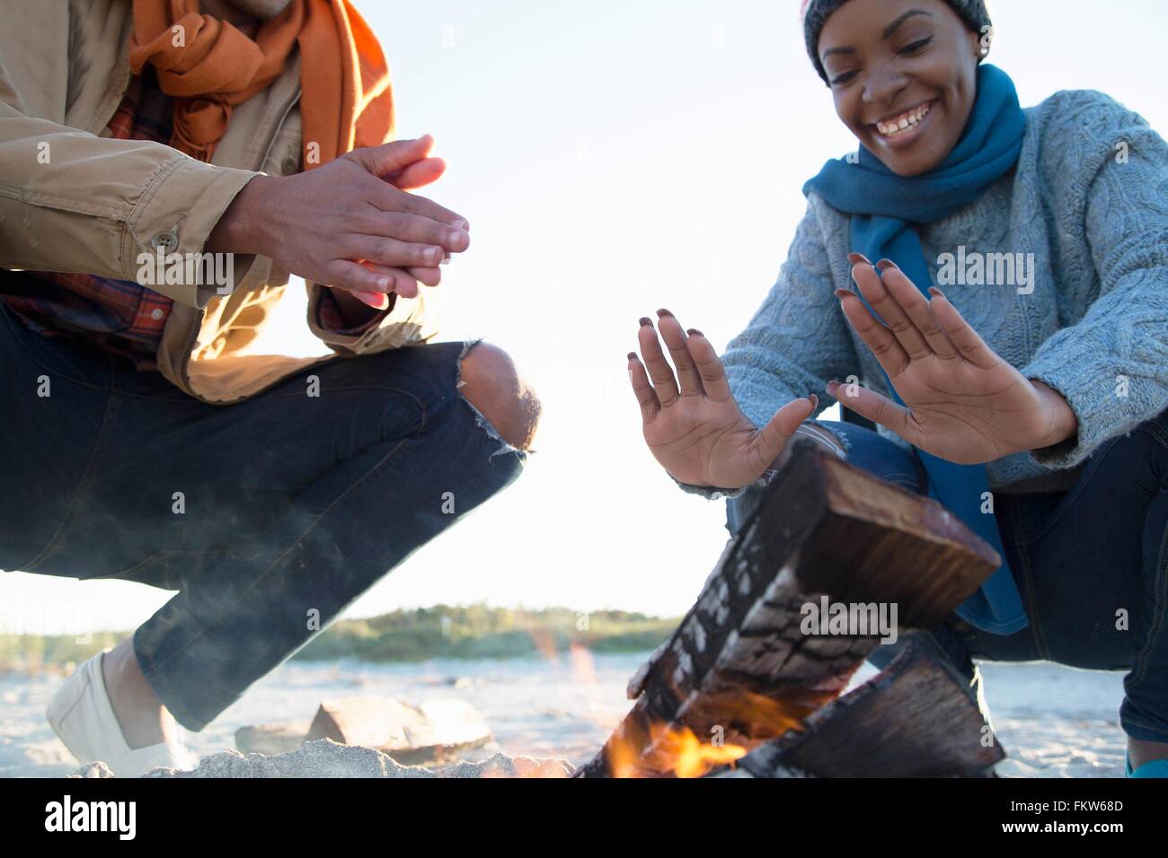 Amici riscaldando le mani sul fuoco di campo Foto Stock