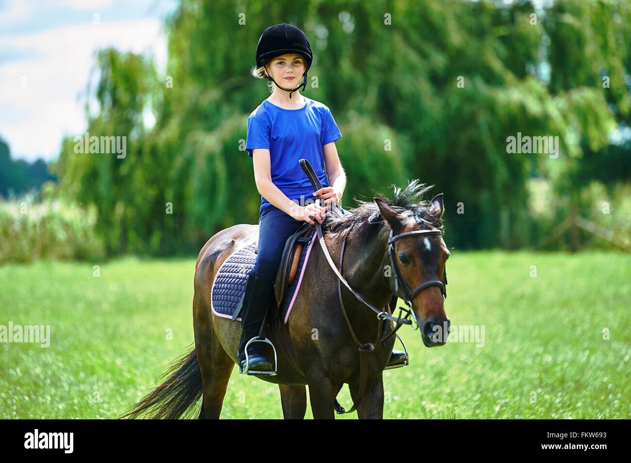 Vista frontale della ragazza a cavallo indossando riding hat guardando sorridente della fotocamera Foto Stock