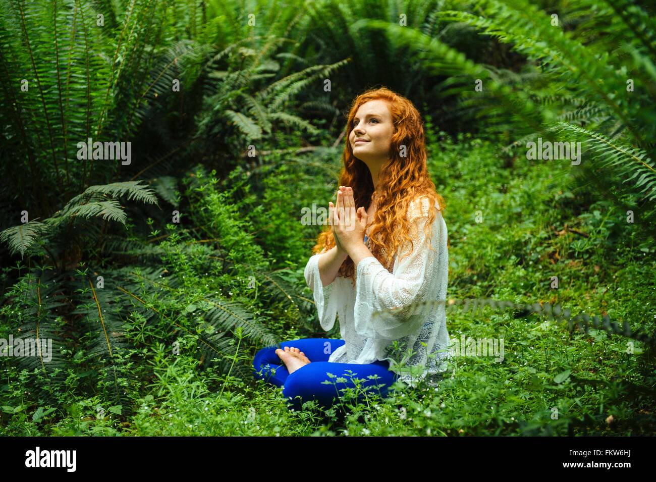 Giovane donna nella foresta a praticare yoga nella posizione del loto Foto Stock