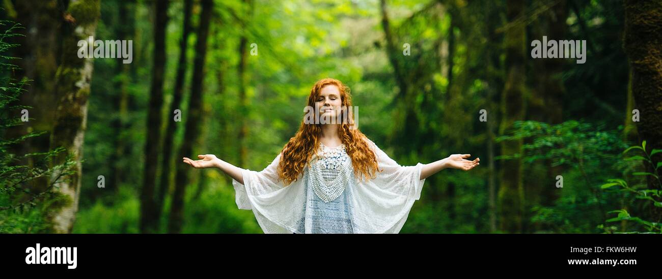 Immagine panoramica della giovane donna meditando con i bracci aperti in foresta Foto Stock