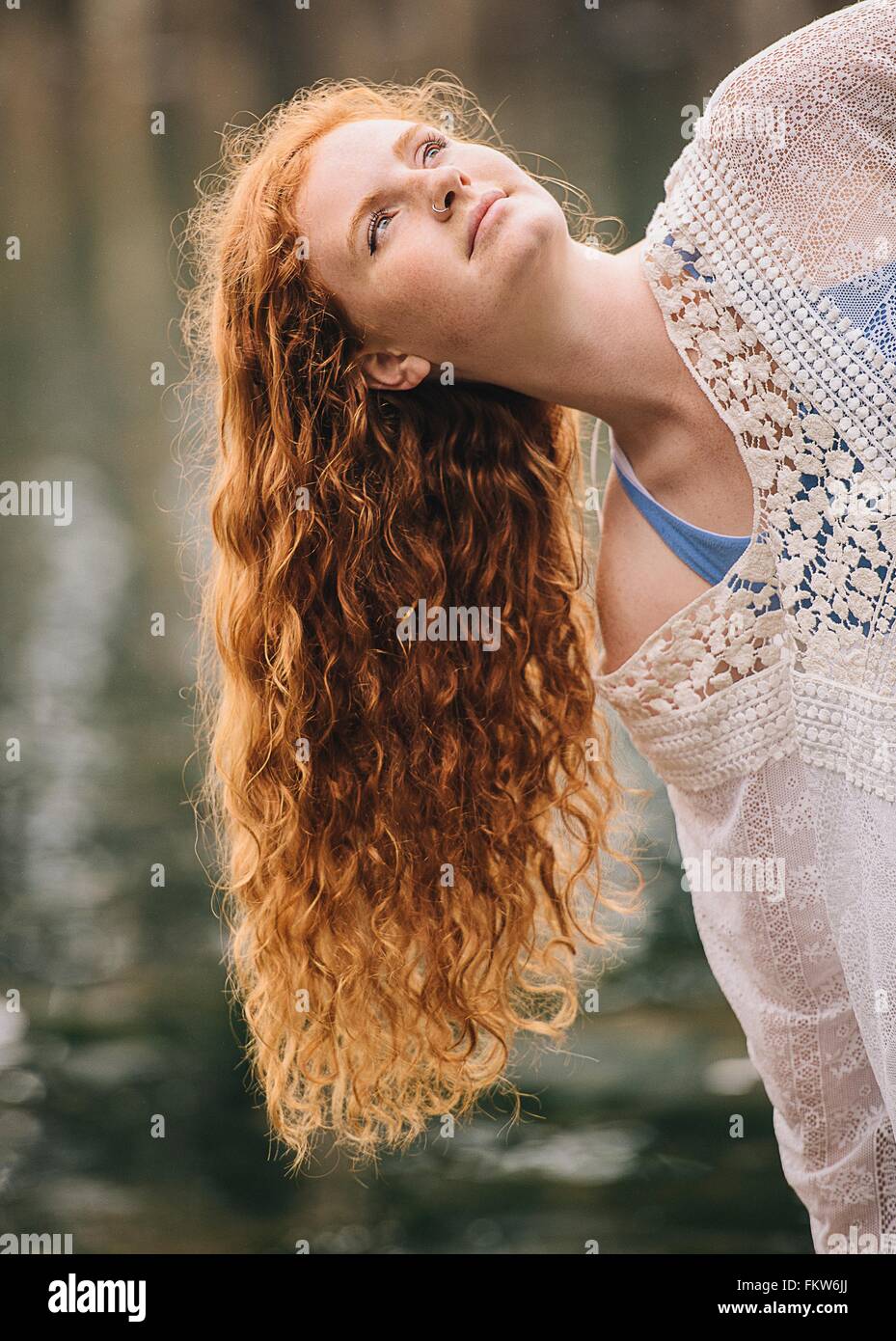 Ritratto di serena giovane donna con lunghi capelli rossi guardando dal fiume Foto Stock