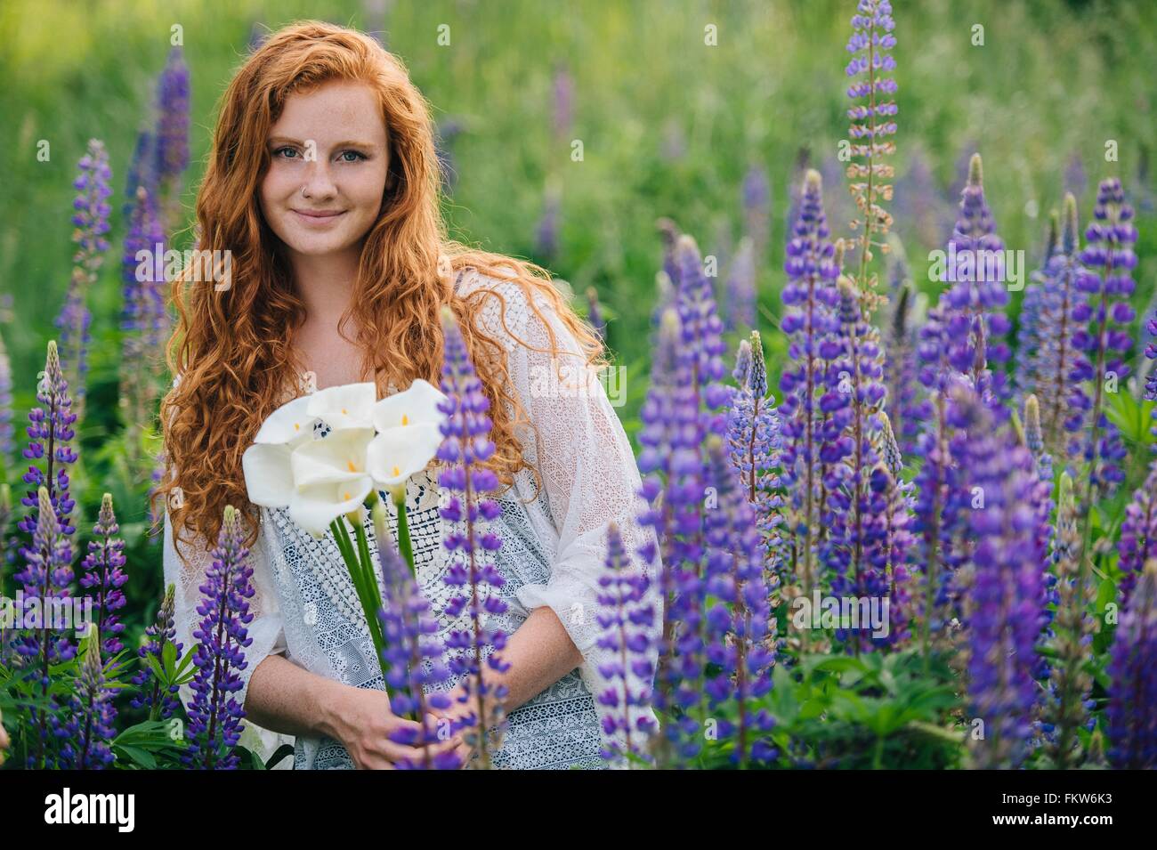Ritratto di giovane donna tra i fiori selvatici viola holding mazzetto di gigli Foto Stock