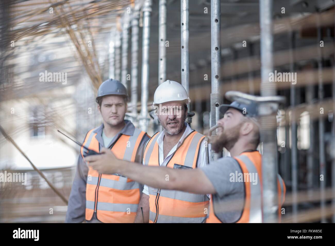 Il Site manager e costruttori che puntano a tondini di acciaio sul sito in costruzione Foto Stock