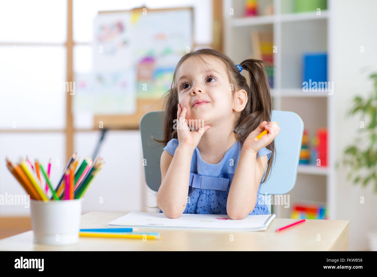 Bambino sognante ragazza di Disegno con matite di colore Foto Stock
