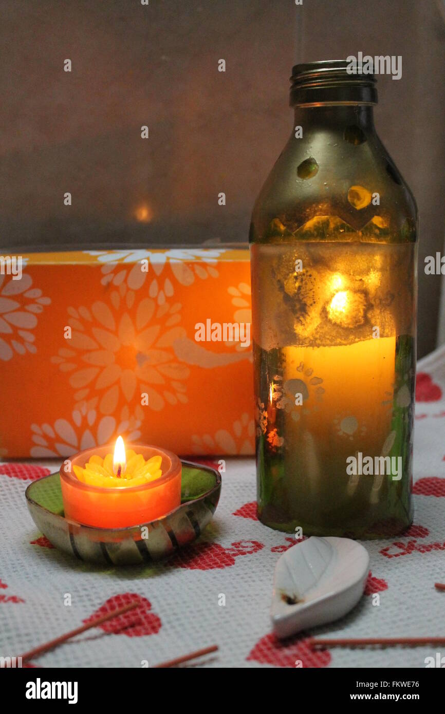 Orange candele in forma di fiori masterizzare in fragili flacone in vetro decorato come paralume Foto Stock