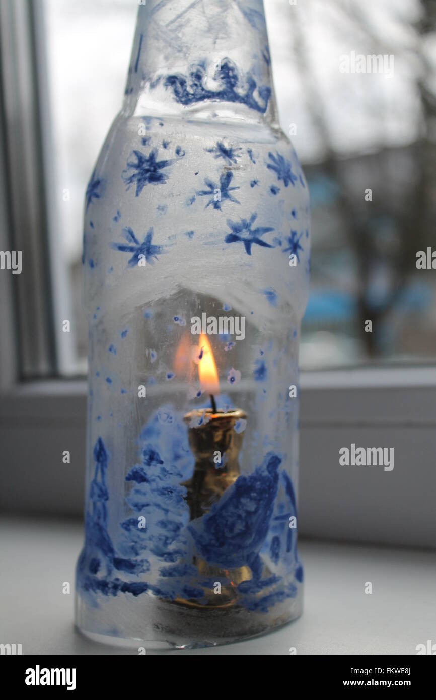 Fragile vaso di vetro con le foto del paese di inverno di notte con un luminoso masterizzare candela interna Foto Stock