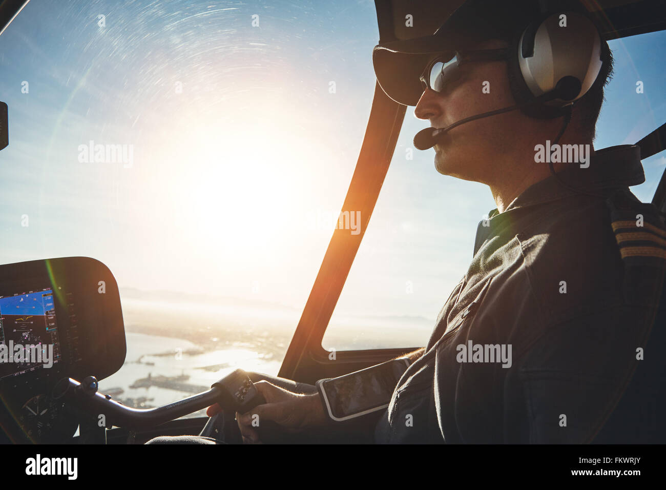 Close up di un pilota di volare a bordo di un elicottero con sun flare entrando nel pozzetto. Foto Stock