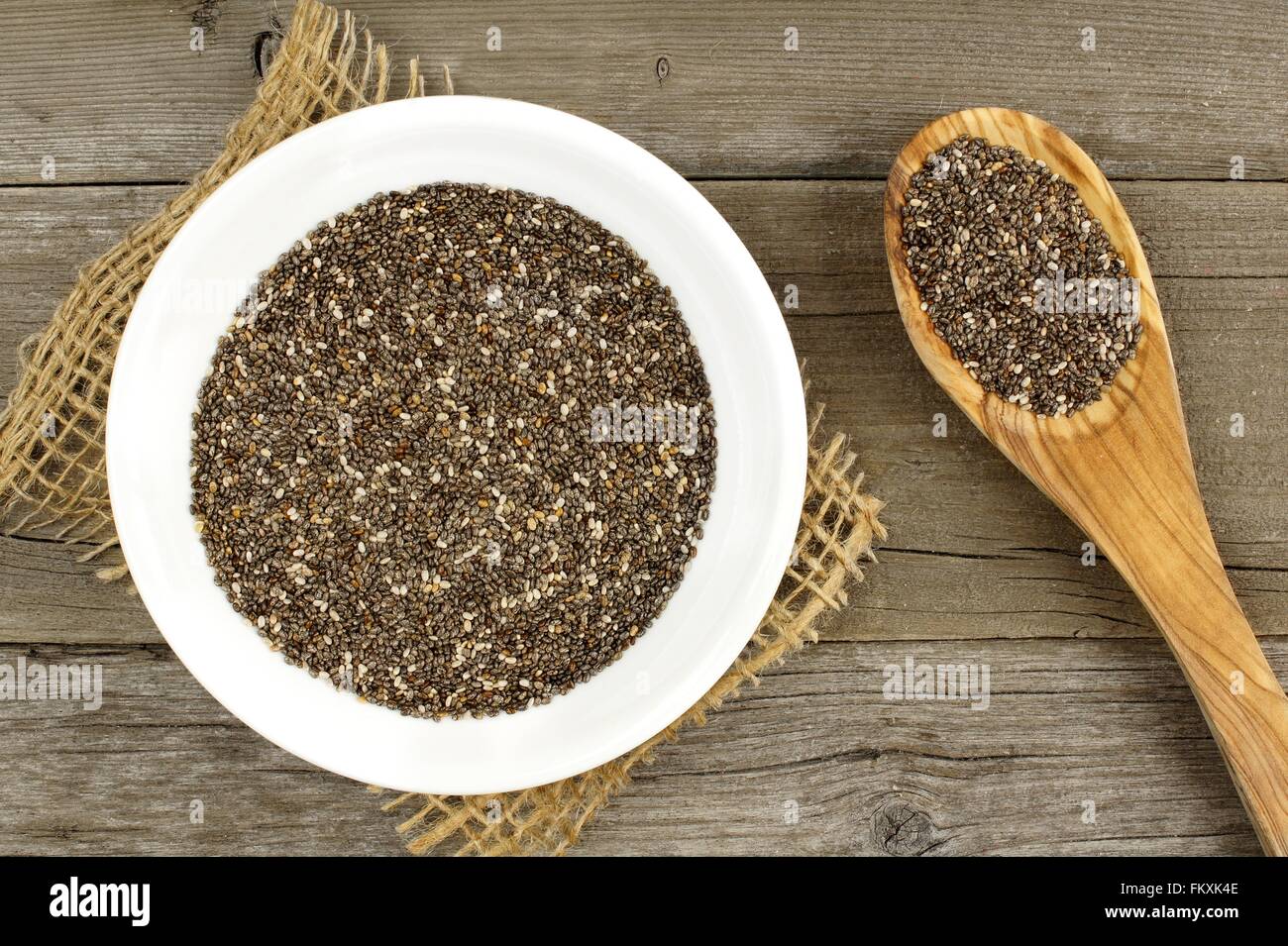 Ciotola e cucchiaio riempito con semi di chia su uno sfondo di legno Foto Stock