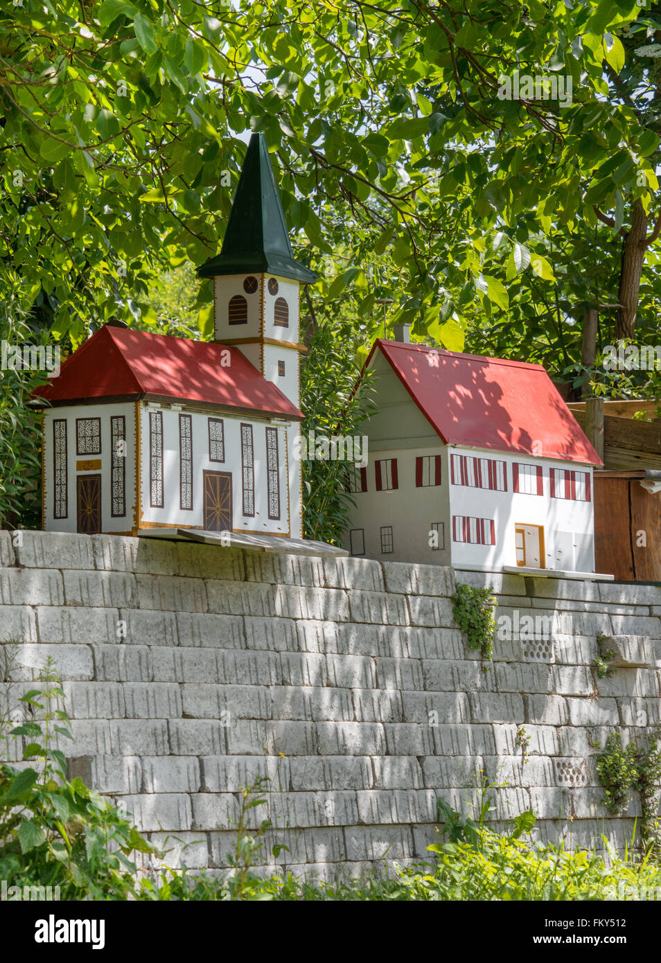 Due singole case di api nella forma di una chiesa e di una casa su una parete sotto gli alberi. Foto Stock