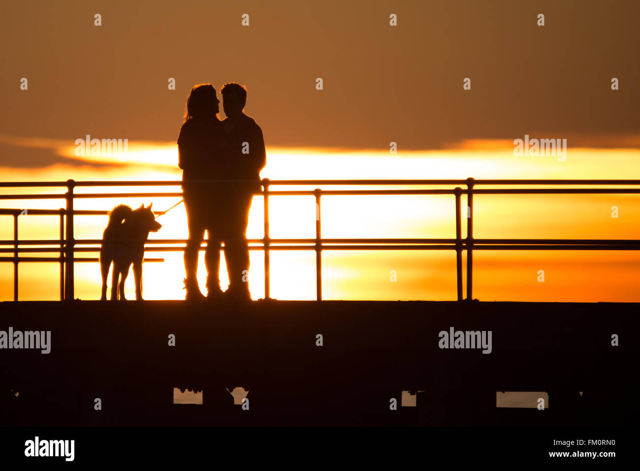 Un paio di abbracciare lungo il pontile in legno sulla costa occidentale del Galles, UK. Credito: Ian Jones/Alamy Live News Foto Stock