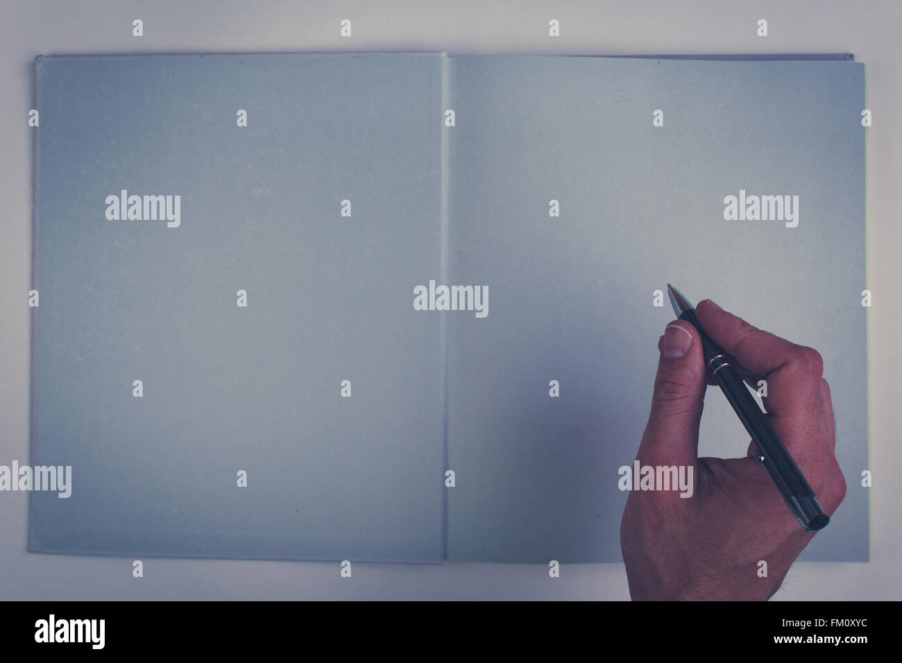 La scrittura a mano nel libro vuoto - mantenimento di una matita su una pagina vuota di un fotolibro vuoto Foto Stock