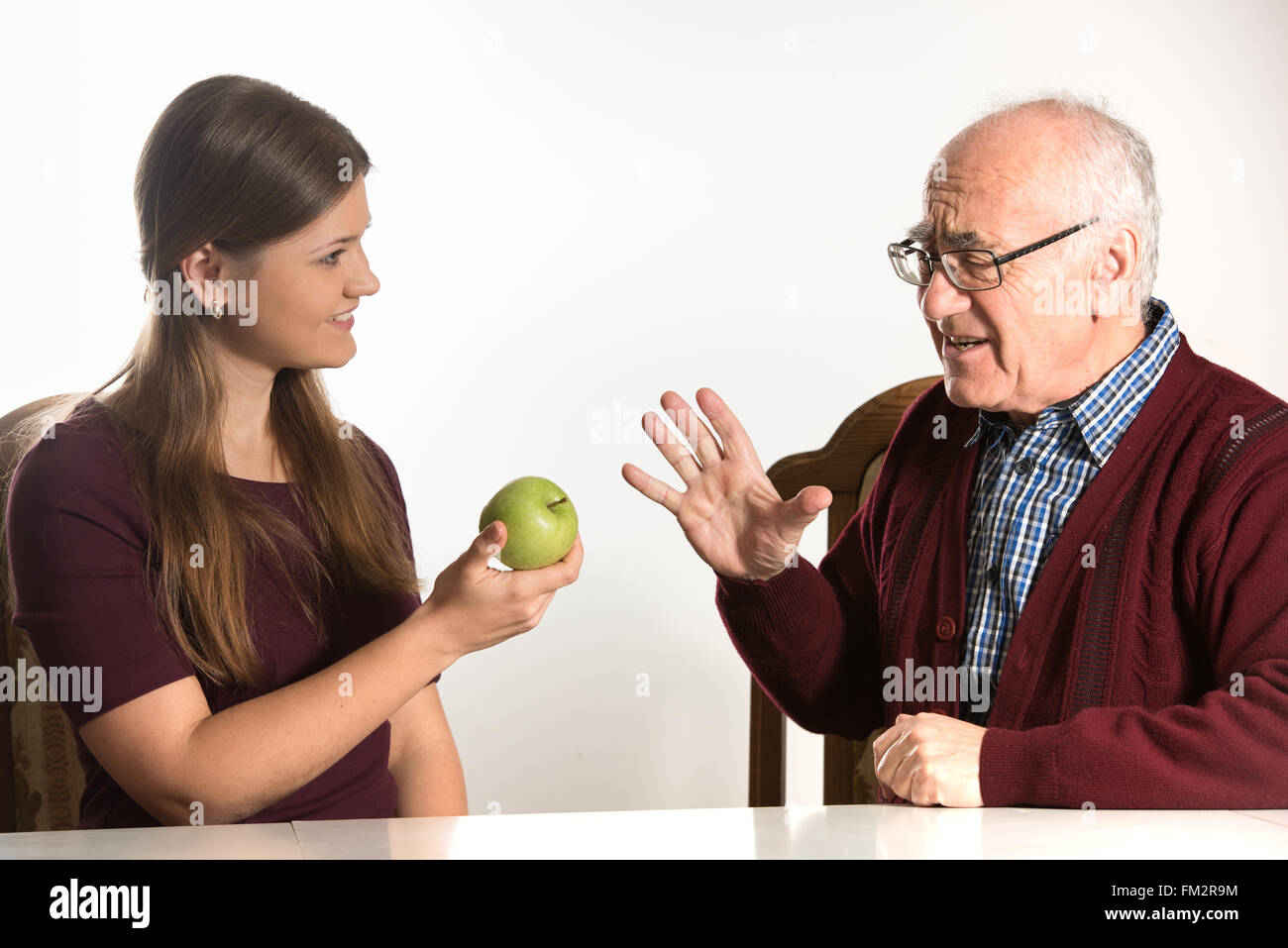 Giovane donna senior aiuta l uomo a mangiare mela verde Foto Stock