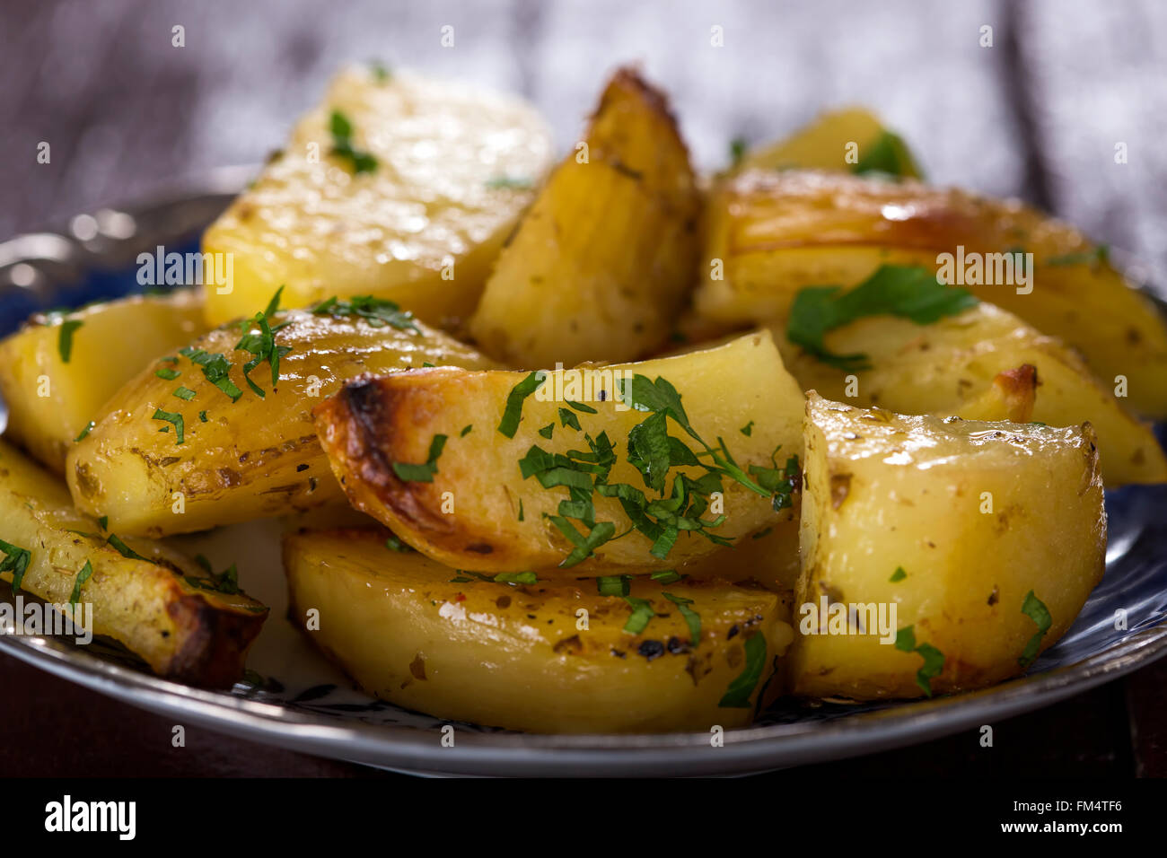 Close up di patate al forno cunei con prezzemolo sulla piastra Foto Stock