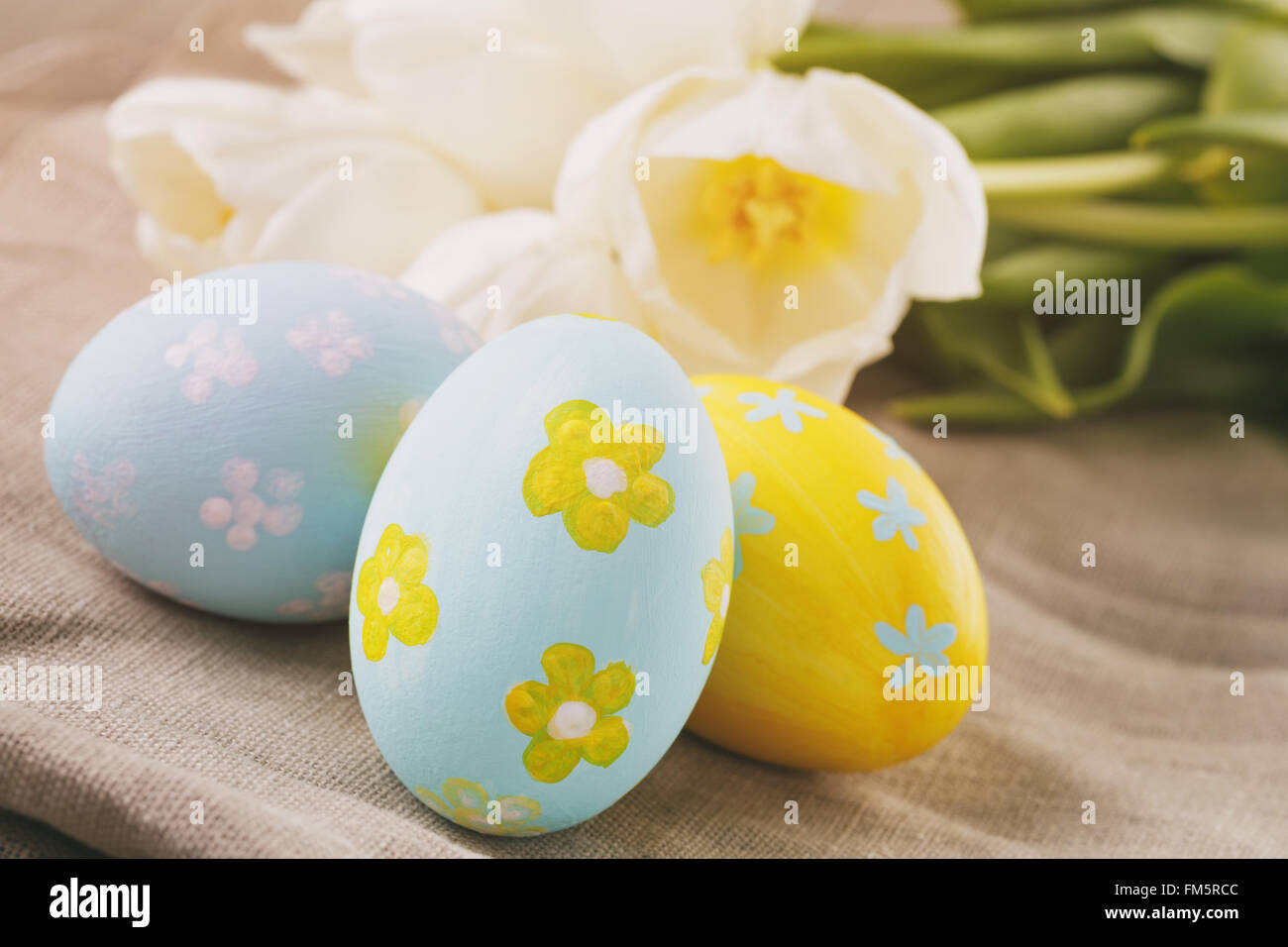 Dipinto a mano le uova di pasqua sulla tabella con i tulipani Foto Stock