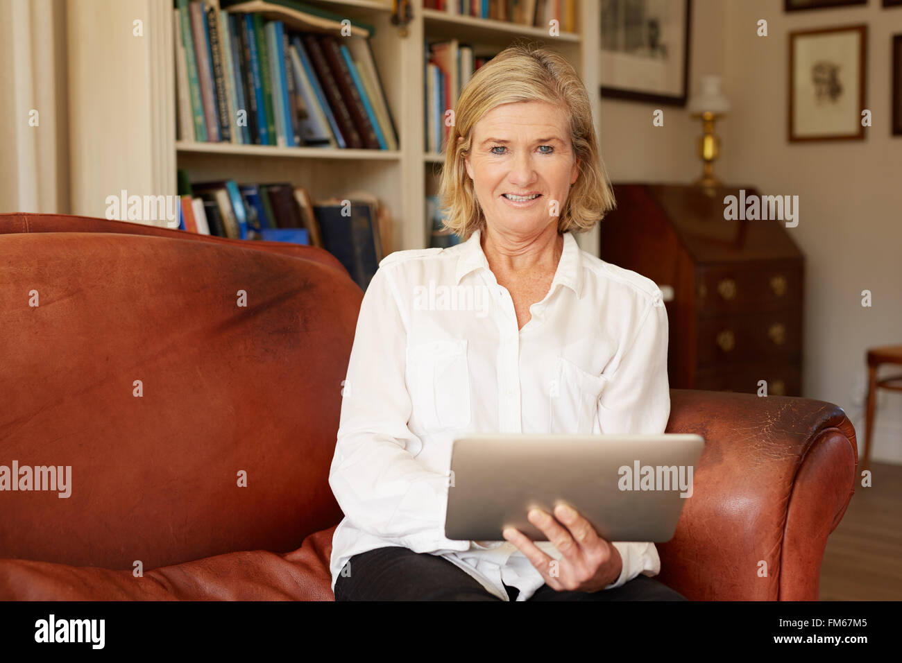 Ritratto di una donna senior in soggiorno con tablet Foto Stock