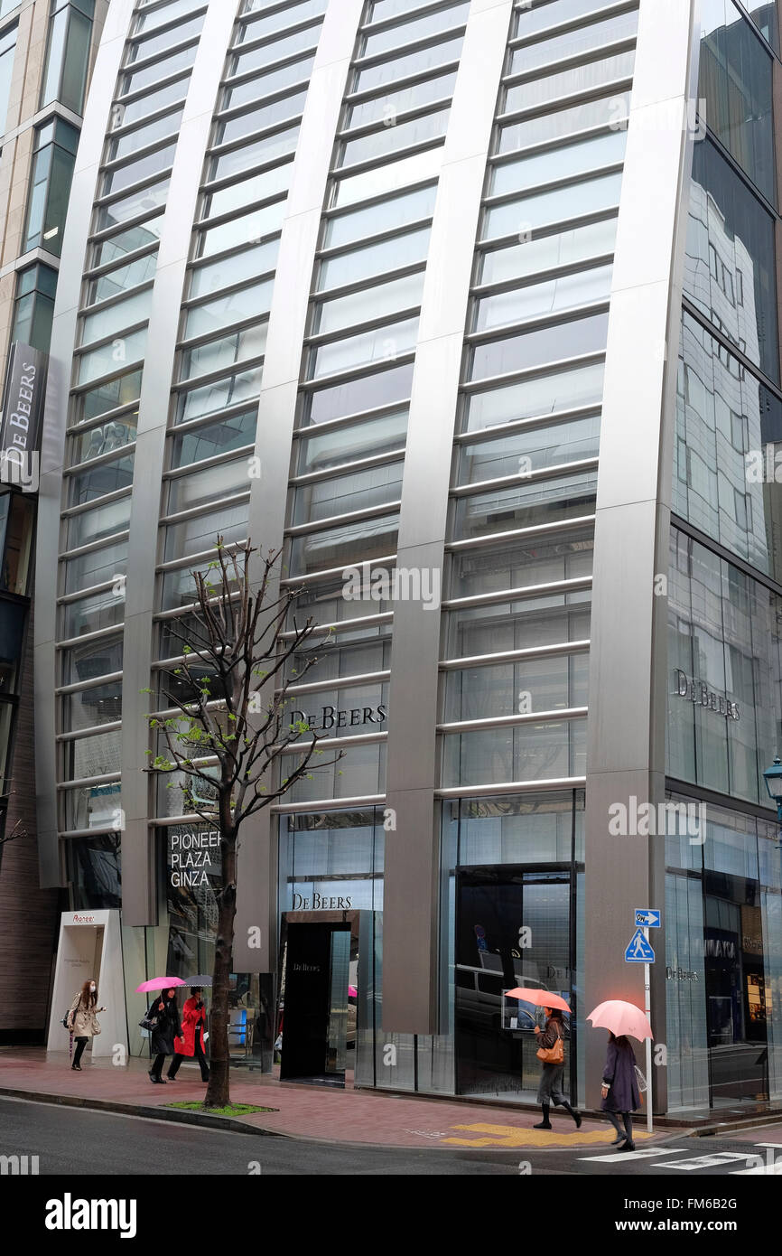 Una vista esterna della sezione di fondo di un ultra moderno edificio chiamato la De Beers edificio in Tokyo, con cinque donna passato a piedi, quattro sollevata con ombrelloni. Foto Stock